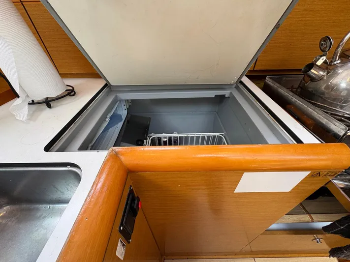Layover Yacht Photos Pics Open fridge in 2018 Jeanneau Sun Odyssey 389 yacht kitchen, showcasing storage space.