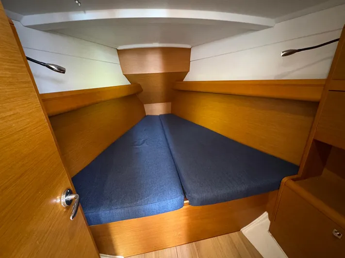 Layover Yacht Photos Pics 2018 Jeanneau Sun Odyssey 389 cabin with blue cushions and wooden interior.