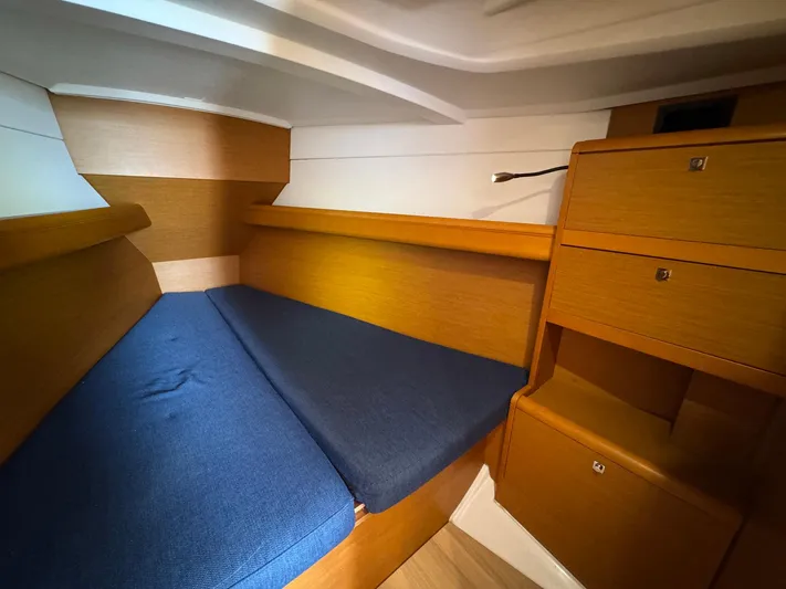 Layover Yacht Photos Pics 2018 Jeanneau Sun Odyssey 389 cabin interior with blue cushions and wooden storage.