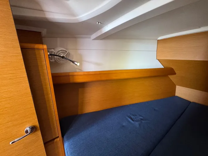 Layover Yacht Photos Pics Interior cabin of 2018 Jeanneau Sun Odyssey 389 with wooden finish and blue bedding.