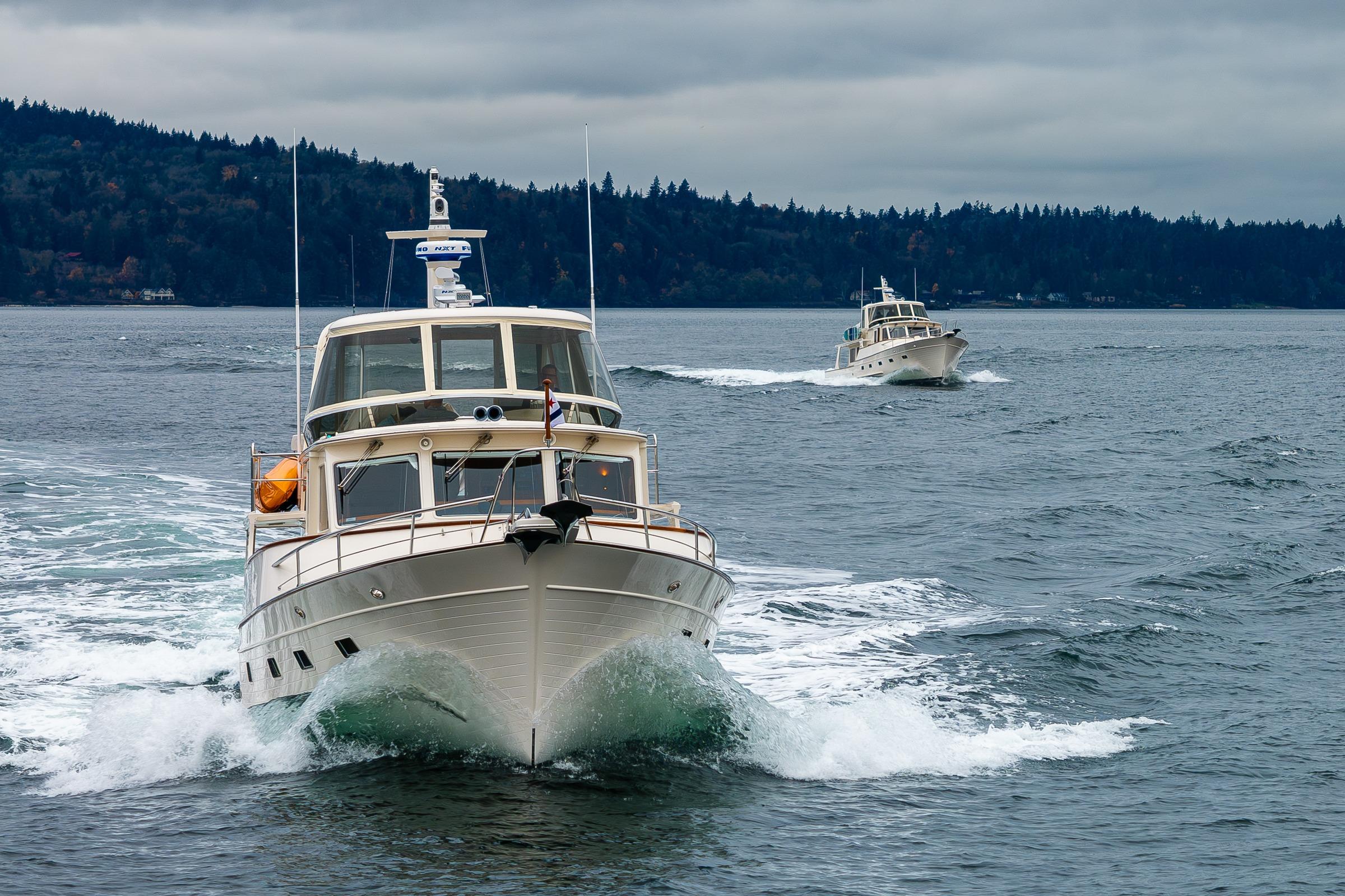 2026 Fleming 55 Pilothouse yachts cruising on a scenic, overcast waterway.