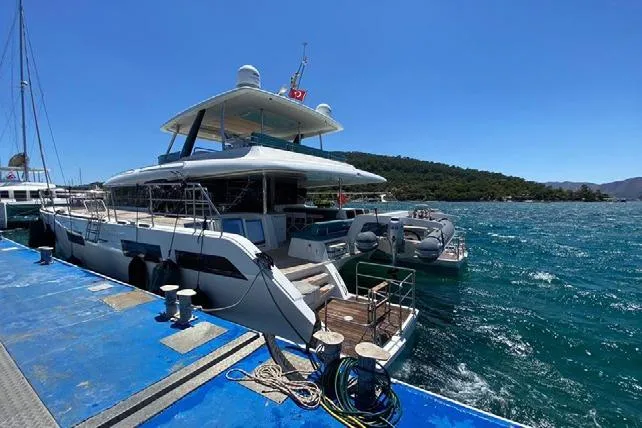  Yacht Photos Pics 2019 Lagoon 630 Motor Yacht docked at a marina with scenic ocean view.