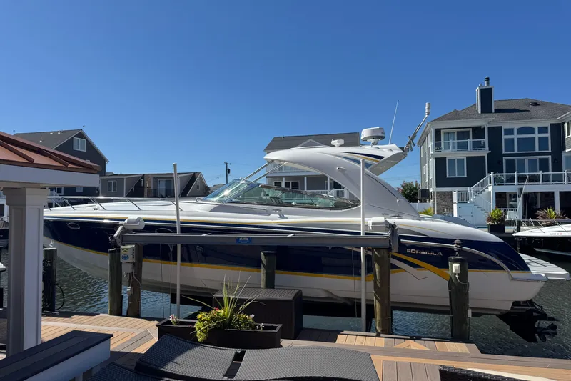  Yacht Photos Pics 2006 Formula 400 Super Sport boat docked near waterfront homes under clear blue sky.