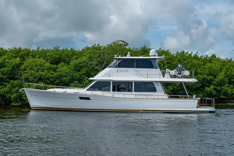 Painkiller Yacht Photos Pics 2023 Grand Banks GB60 yacht cruising on a calm river, lush greenery in the background.