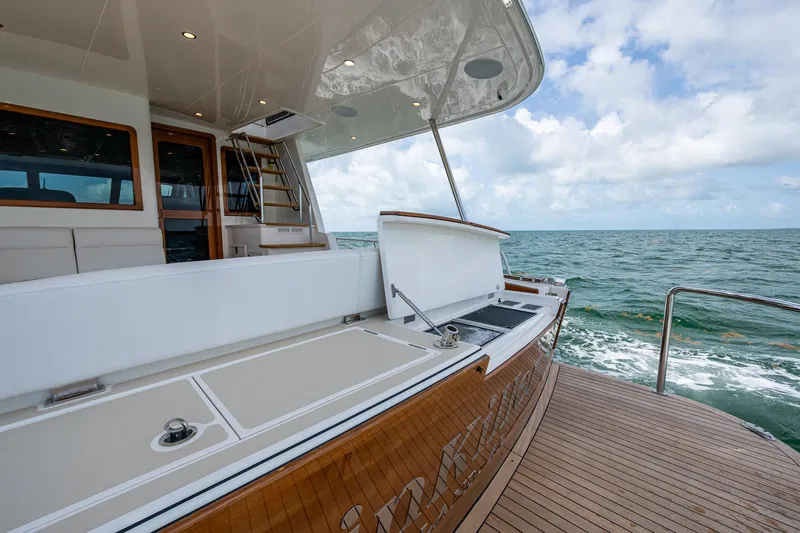 Painkiller Yacht Photos Pics 2023 Grand Banks GB60 yacht deck with ocean view, featuring elegant wood and white finishes.
