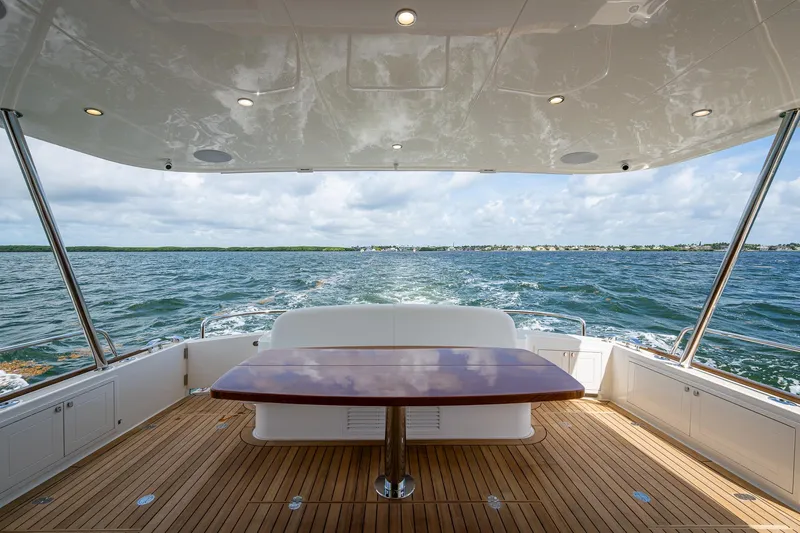 Painkiller Yacht Photos Pics 2023 Grand Banks GB60 yacht deck with ocean view and elegant wooden table.