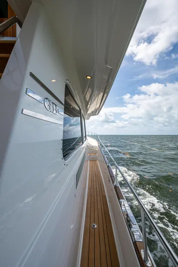 Painkiller Yacht Photos Pics 2023 Grand Banks GB60 yacht side view with teak deck and ocean backdrop.