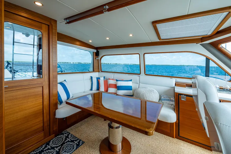 Painkiller Yacht Photos Pics Luxurious 2023 Grand Banks GB60 yacht interior with ocean view, featuring elegant wood and white seating.