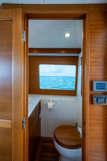 Painkiller Yacht Photos Pics 2023 Grand Banks GB60 yacht bathroom with ocean view, wooden interior, and modern fixtures.