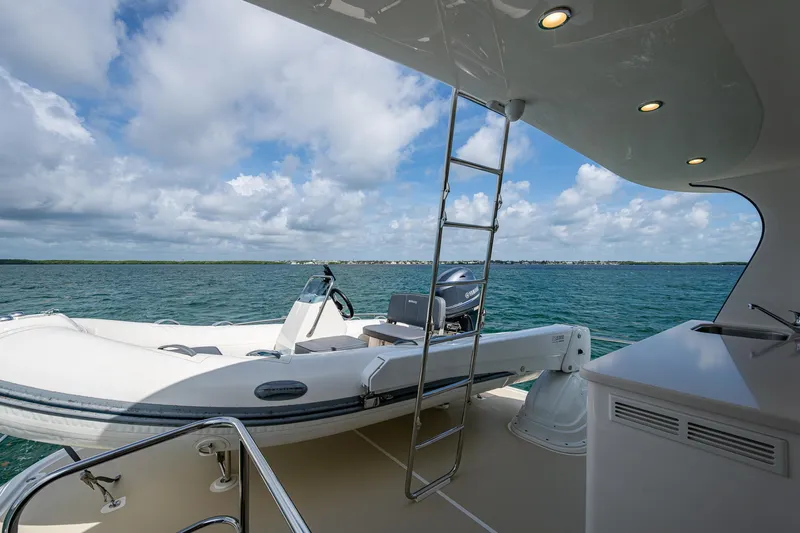 Painkiller Yacht Photos Pics 2023 Grand Banks GB60 yacht with tender, ladder, and ocean view under cloudy sky.