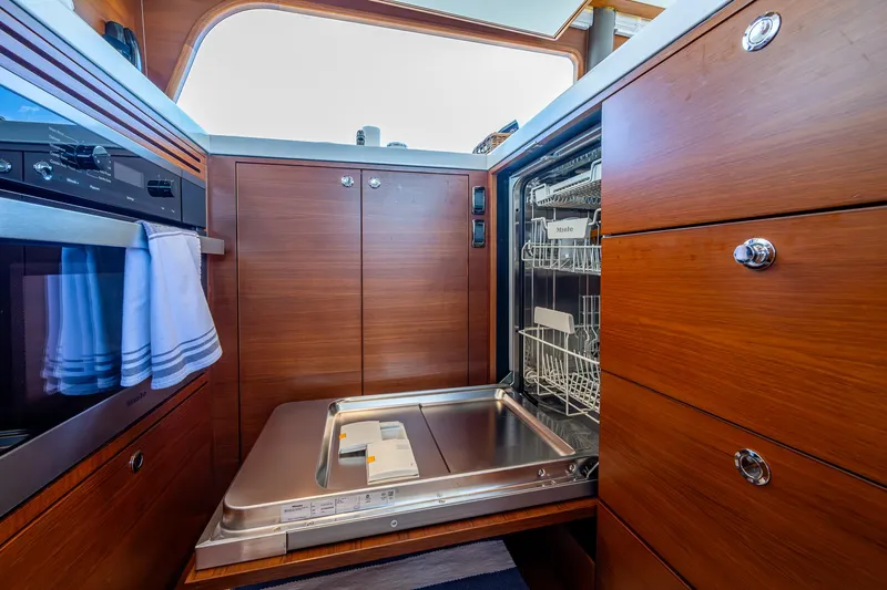 Painkiller Yacht Photos Pics Luxury yacht kitchen with open dishwasher, wooden cabinetry, and modern appliances on a 2023 Grand Banks GB60.