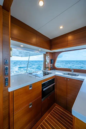 Painkiller Yacht Photos Pics Luxurious 2023 Grand Banks GB60 yacht kitchen with ocean view, featuring modern wood cabinetry and appliances.