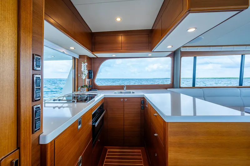 Painkiller Yacht Photos Pics Luxurious 2023 Grand Banks GB60 yacht kitchen with ocean view, featuring modern wood cabinetry.