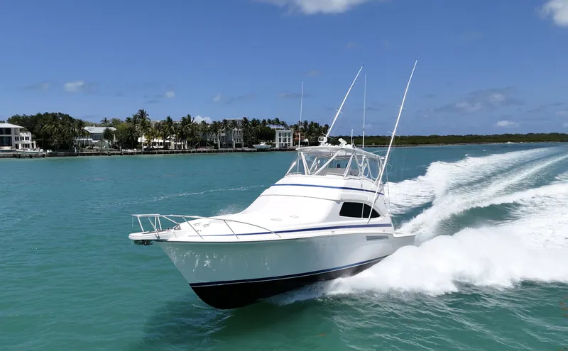  Yacht Photos Pics 2007 Bertram 570 yacht cruising on turquoise water near a tropical shoreline.