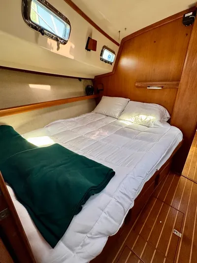 TinteÁn Yacht Photos Pics Cozy cabin interior of 2000 Island Packet 40 sailboat with bed and wooden accents.
