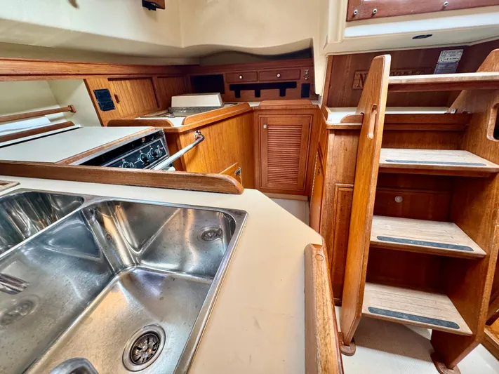 TinteÁn Yacht Photos Pics Interior of 2000 Island Packet 40 sailboat, featuring a kitchen sink and wooden cabinetry.