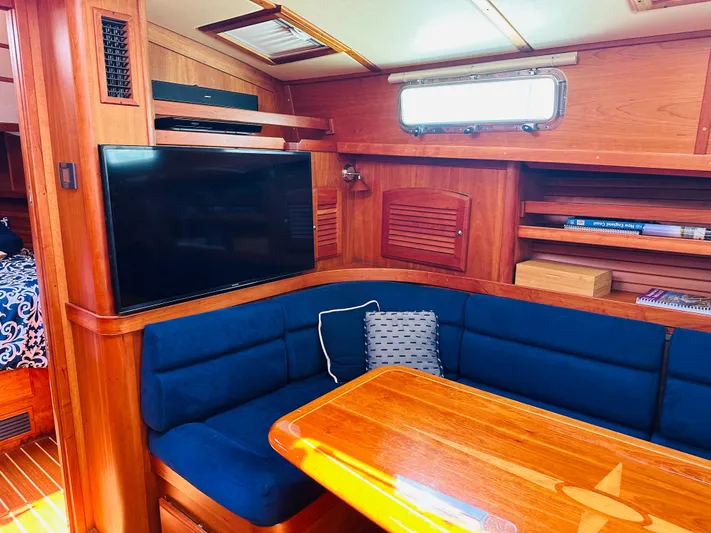 Slipped Away Yacht Photos Pics Interior of 2008 Sabre 42 Hardtop Express with blue seating, wooden table, and TV.
