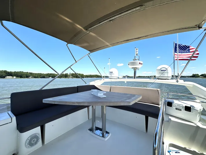  Yacht Photos Pics Luxurious 2017 Prestige 500 yacht deck with seating, table, and American flag on a sunny day.