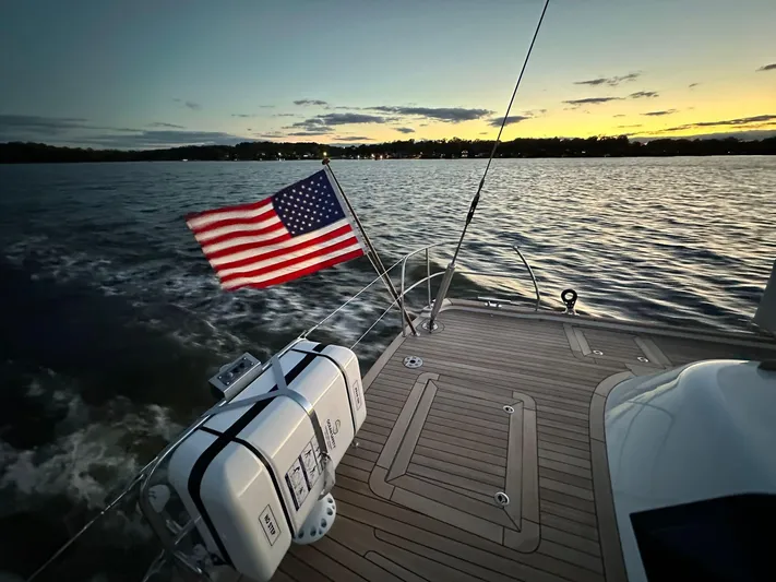 Pinnacle Yacht Photos Pics Hallberg-Rassy 57 yacht deck at sunset, American flag waving, 2023 model.