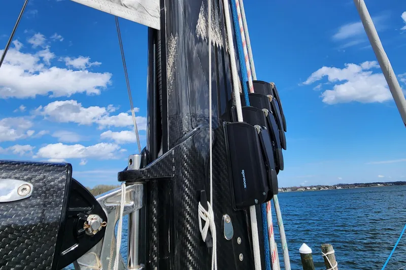 Pinnacle Yacht Photos Pics 2023 Hallberg-Rassy 57 sailboat mast with rigging against blue sky and water backdrop.