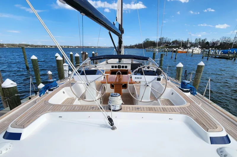 Pinnacle Yacht Photos Pics 2023 Hallberg-Rassy 57 yacht docked, showcasing dual steering wheels and teak deck.