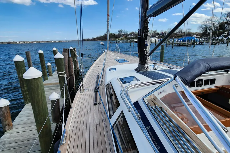 Pinnacle Yacht Photos Pics 2023 Hallberg-Rassy 57 yacht docked by a serene waterfront.