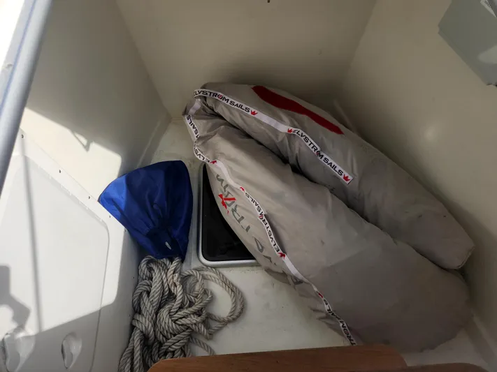 Pinnacle Yacht Photos Pics Storage compartment on 2023 Hallberg-Rassy 57 yacht with sail, rope, and blue cover.