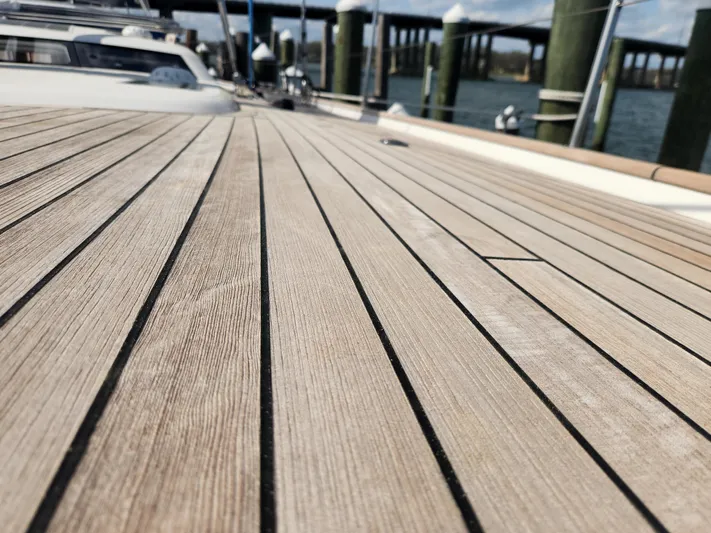 Pinnacle Yacht Photos Pics Teak deck of 2023 Hallberg-Rassy 57 yacht at a marina.