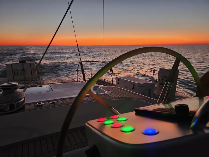 Pinnacle Yacht Photos Pics 2023 Hallberg-Rassy 57 yacht at sunset, featuring illuminated controls and ocean view.