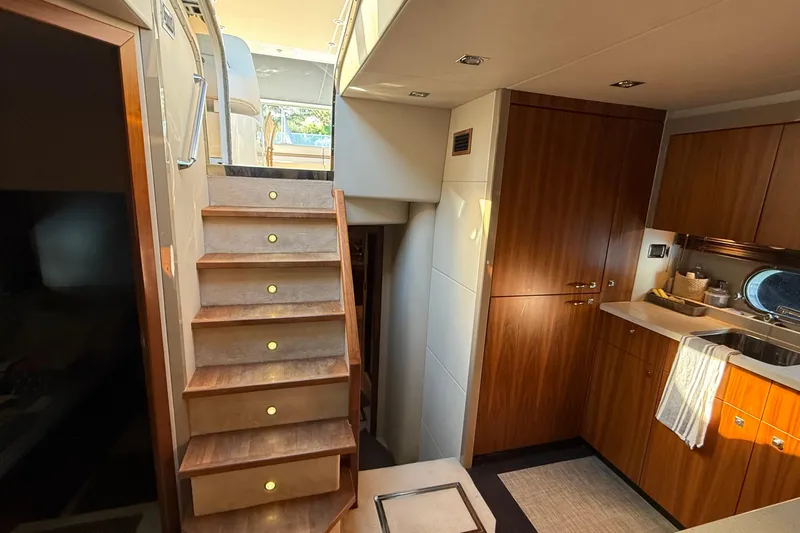 Helios Yacht Photos Pics Luxurious interior of 2010 Sunseeker Predator 60 yacht with wooden cabinetry and staircase.