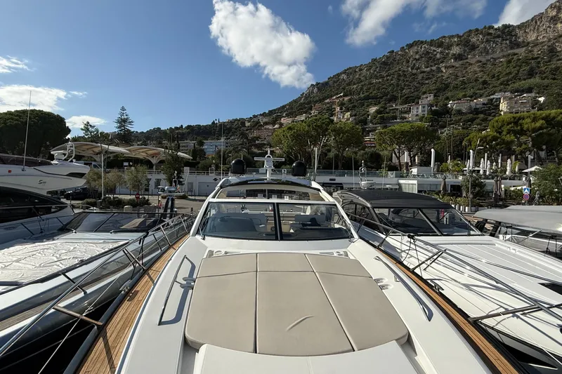 Helios Yacht Photos Pics 2010 Sunseeker Predator 60 yacht docked in a scenic marina with hillside backdrop.