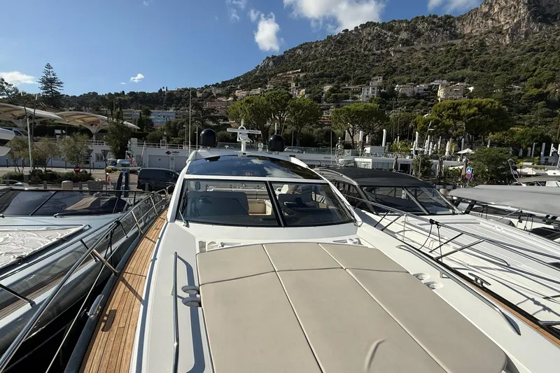 Helios Yacht Photos Pics 2010 Sunseeker Predator 60 yacht docked in a scenic marina with hillside backdrop.
