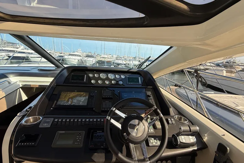 Helios Yacht Photos Pics Cockpit view of 2010 Sunseeker Predator 60 yacht, showcasing navigation controls and marina backdrop.