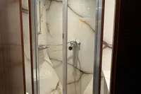 Compact marble shower with glass doors in a vintage 1958 Custom model 22.