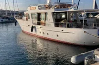 Vintage 1958 Custom yacht docked in marina, clear sky, calm water.
