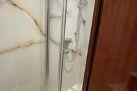 Luxurious shower with glass doors and marble walls in a vintage 1958 Custom model 22.