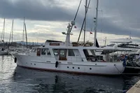 Vintage 1958 Custom yacht docked in marina under cloudy sky.