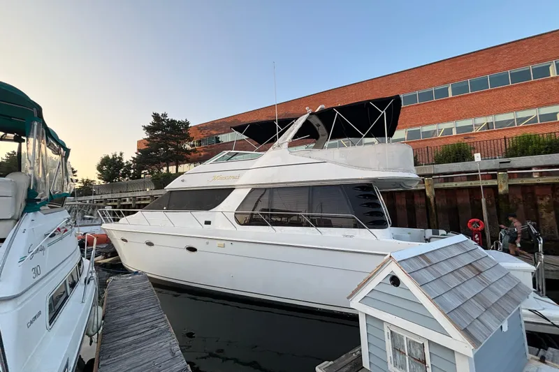 Moonstruck Yacht Photos Pics 1998 Carver 530 Voyager Pilothouse yacht docked at marina, near brick building.