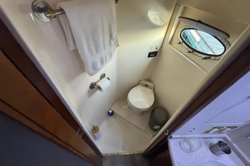 Moonstruck Yacht Photos Pics Bathroom in 1998 Carver 530 Voyager Pilothouse with porthole, toilet, and towel rack.