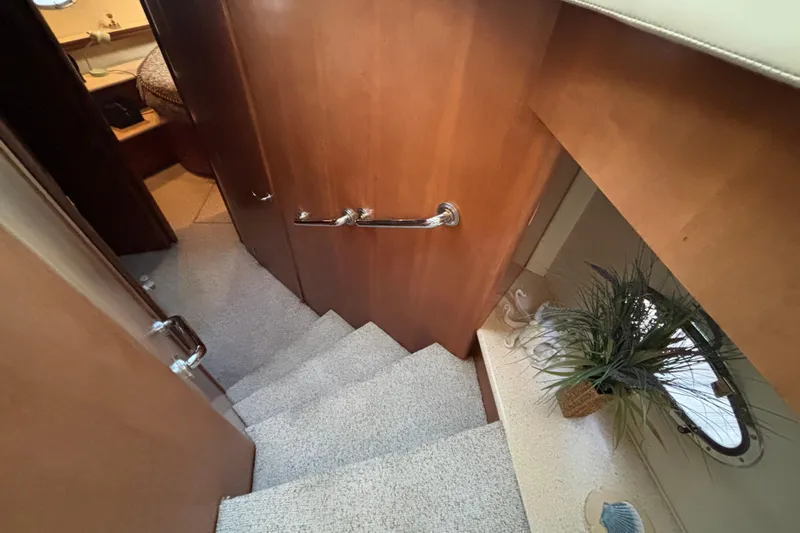 Moonstruck Yacht Photos Pics Interior stairs of 1998 Carver 530 Voyager Pilothouse with wooden paneling and porthole.