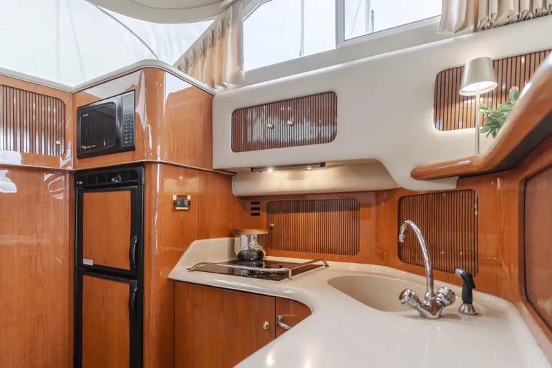 Waterfront Property Yacht Photos Pics Interior kitchen of 2000 Sea Ray 400 Sedan Bridge yacht with wooden cabinetry and modern appliances.