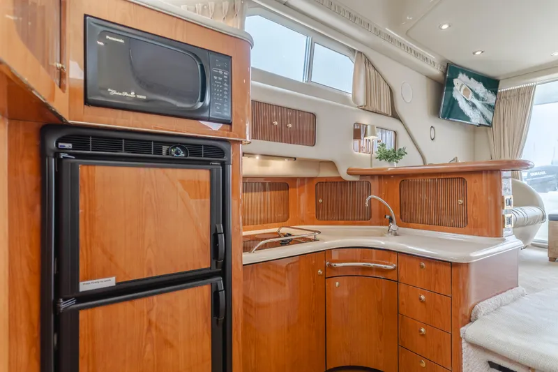 Waterfront Property Yacht Photos Pics 2000 Sea Ray 400 Sedan Bridge kitchen with wood cabinetry, microwave, and refrigerator.