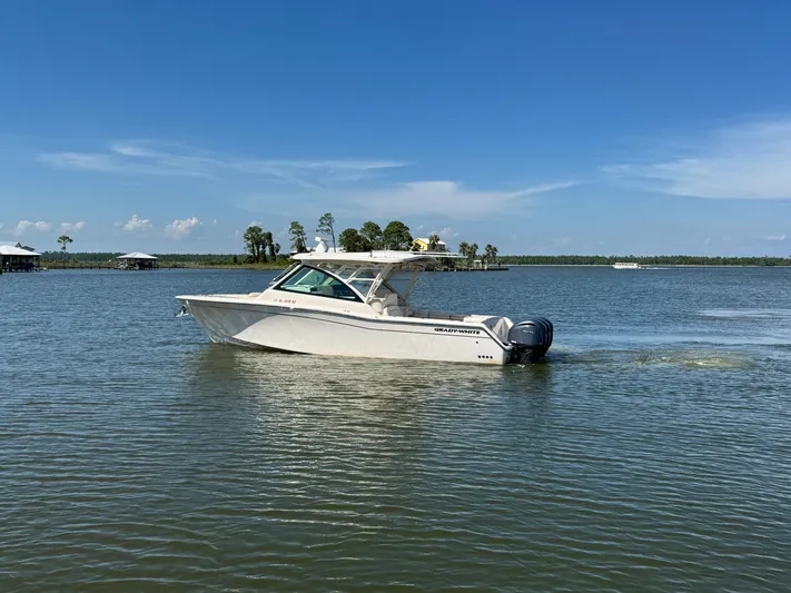  Yacht Photos Pics 2021 Grady-White Freedom 375 boat cruising on a calm lake under a clear blue sky.