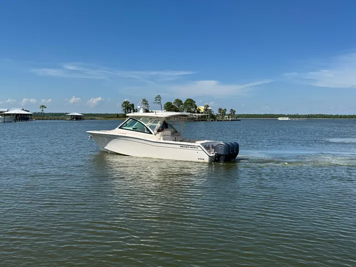  Yacht Photos Pics 2021 Grady-White Freedom 375 boat cruising on a calm lake under a clear blue sky.