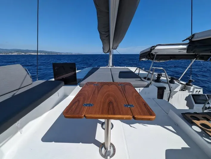 Yacht Photos Pics Fountaine Pajot Elba 45 catamaran deck with wooden table, 2022 model, sailing on open sea.