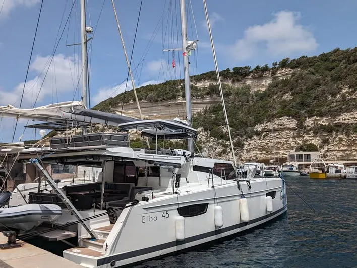  Yacht Photos Pics 2022 Fountaine Pajot Elba 45 catamaran docked in scenic marina with cliffs.