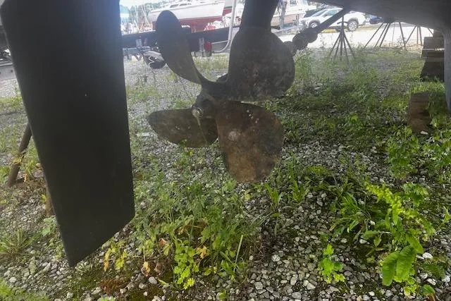 Talisman Yacht Photos Pics Propeller of 2003 Mainship 430 Aft Cabin Trawler on gravel with greenery.