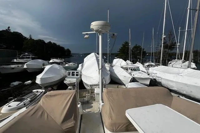 Talisman Yacht Photos Pics 2003 Mainship 430 Aft Cabin Trawler docked among covered boats under cloudy sky.