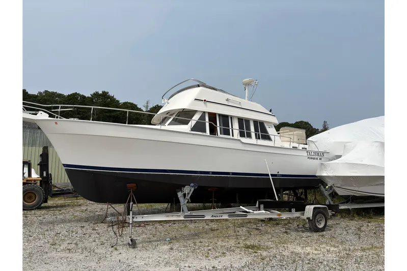Talisman Yacht Photos Pics 2003 Mainship 430 Aft Cabin Trawler on trailer, parked outdoors.