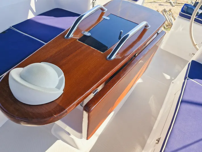  Yacht Photos Pics Wooden cockpit table on 2011 Catalina 445 sailboat, featuring blue cushions and stainless steel handles.
